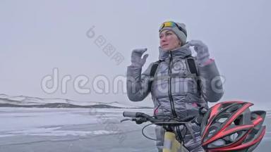 女人穿着运动装备。 女孩穿着银色<strong>羽绒服</strong>，自行车背包和头盔。 冰的冰
